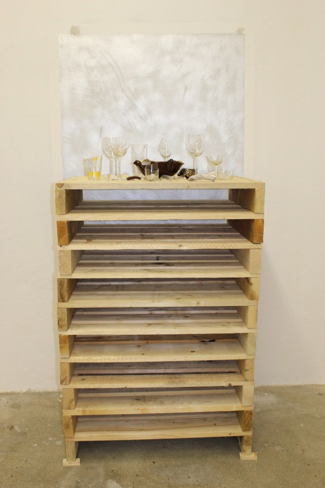 © Renate Egger. Zerbrochene Erinnerungen/Broken memories, 2012. Installation, Fotografie. Gläser, Porzellan, römisches antikes Fragment , Muschel aus Zanzibar auf Holzpaletten/ Installation, photography. Glasses, porcelain, roman antique fragment, shell from Zanzibar on wooden palletts